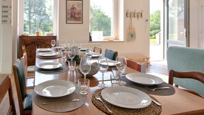 Una tavola da pranzo imbandita per sei persone, con piatti, posate e bicchieri.