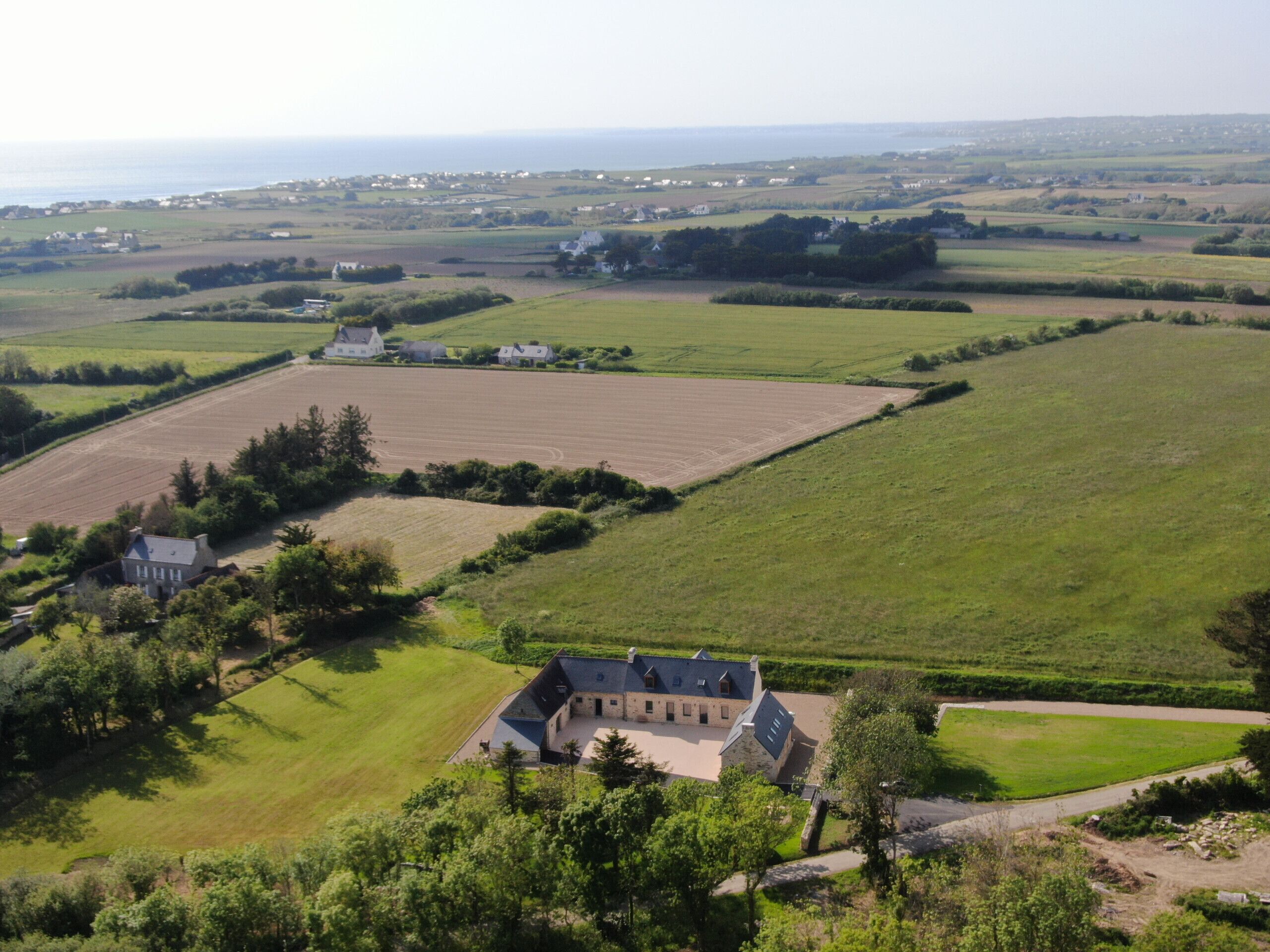 Un vaste domaine comprenant plusieurs bâtiments, de vastes champs et une vue sur la mer.