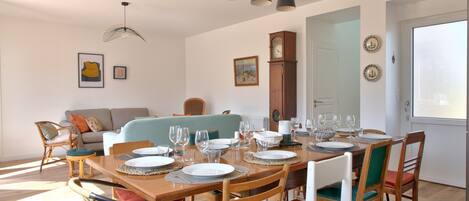 A dining area with a wooden table set for six, surrounded by wicker chairs and a wooden bench.