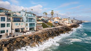 A coastal hotel with multiple floors, a rocky shoreline, and a view of the ocean. - Stunning Oceanfront Home w/ Panoramic Views (Oceanside)