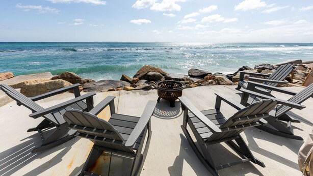 A beachside lounge with Adirondack chairs and a fire pit, overlooking the ocean. - Stunning Oceanfront Home w/ Panoramic Views (Oceanside)