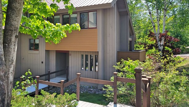 A modern two-story house with a wooden exterior, a front porch, and a stone pathway leading to the entrance. - Open concept, deck, fireplace, AC, pet-friendly, near Loon. C6301 by LRS (Lincoln)