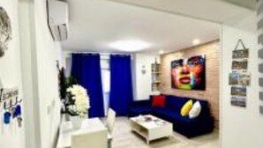 A modern living room with a sofa, coffee table, and a TV mounted on the wall. - Rambla Apartment by the Sea (Alicante (Alacant))