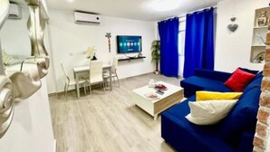 A modern living room with a blue sofa, a coffee table, and a TV. - Rambla Apartment by the Sea (Alicante (Alacant))