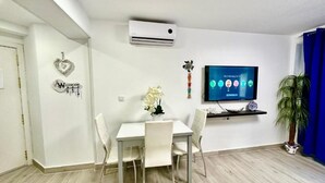 A modern living room with a dining table, chairs, a flat-screen TV, and a potted plant. - Rambla Apartment by the Sea (Alicante (Alacant))