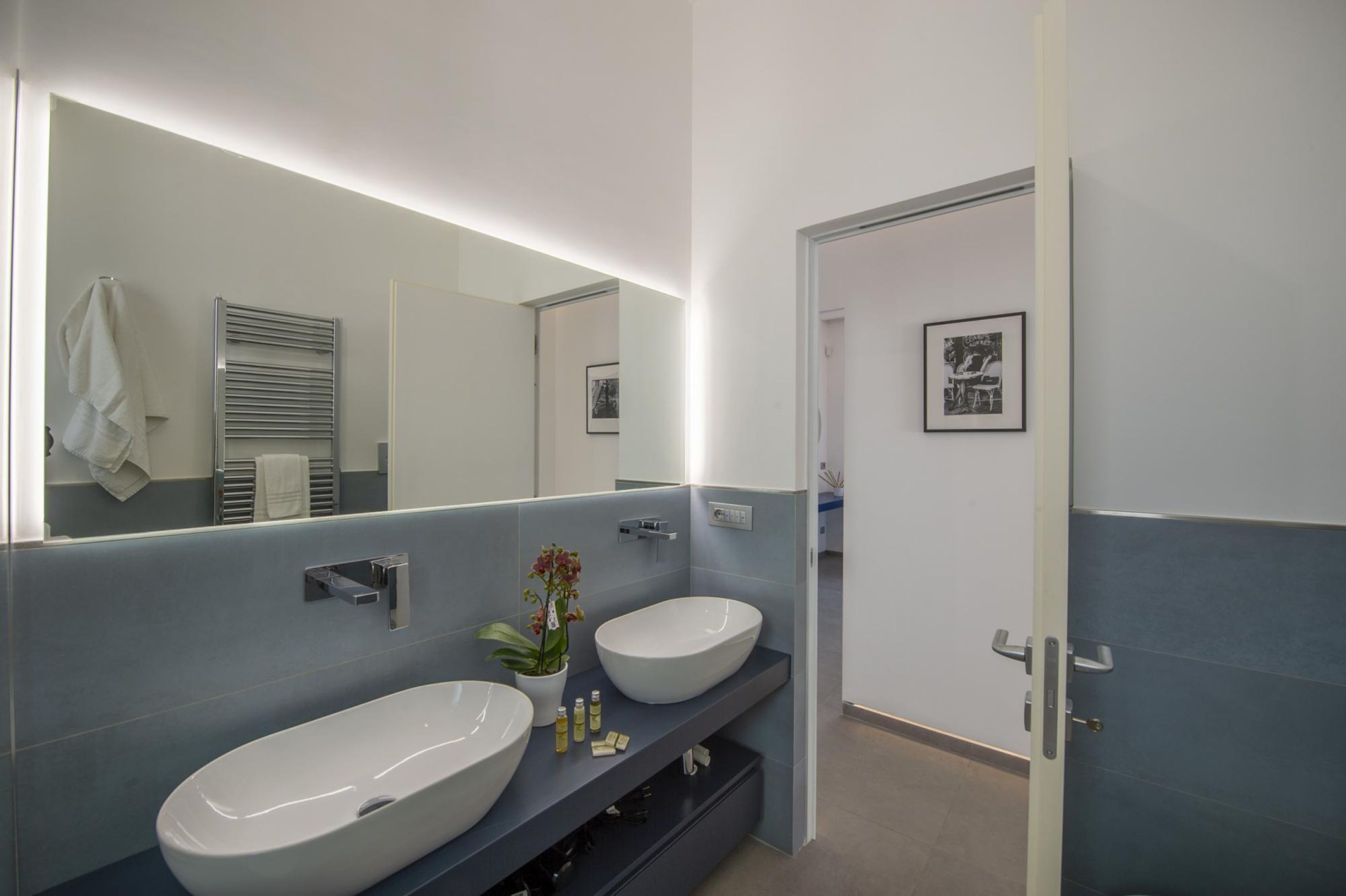 Un baño moderno con dos lavamanos amplios, un espejo y un perchero para toallas.