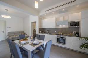 A modern kitchen with white cabinets, a built-in oven, and a microwave.