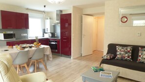 A compact living space with a dining area, kitchenette, and a sofa.