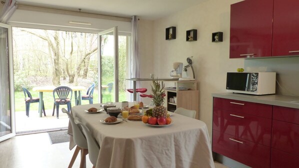 A dining area with a table set for breakfast, a microwave, and red cabinets.