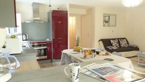 Una cucina moderna con elettrodomestici in acciaio inossidabile, un'area pranzo con prodotti per la colazione e un soggiorno con divano e cuscini.