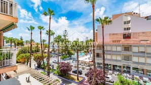 Um hotel com piscina, palmeiras e vista para a cidade.