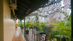 A covered outdoor area with a tiled floor, potted plants, and a table with chairs. - Sophavady D'Angkor (Siem Reap)