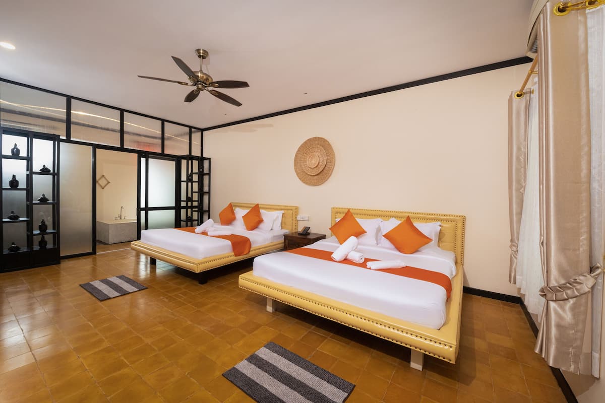 A hotel room with two beds, a ceiling fan, a woven wall hanging, and a sliding glass door leading to a balcony.