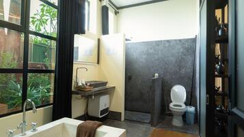A bathroom with a bathtub, sink, toilet, and a shower area.