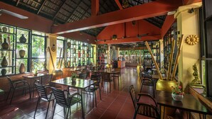 A restaurant with a high ceiling, large windows, and a variety of seating arrangements. - Sophavady D'Angkor (Siem Reap)