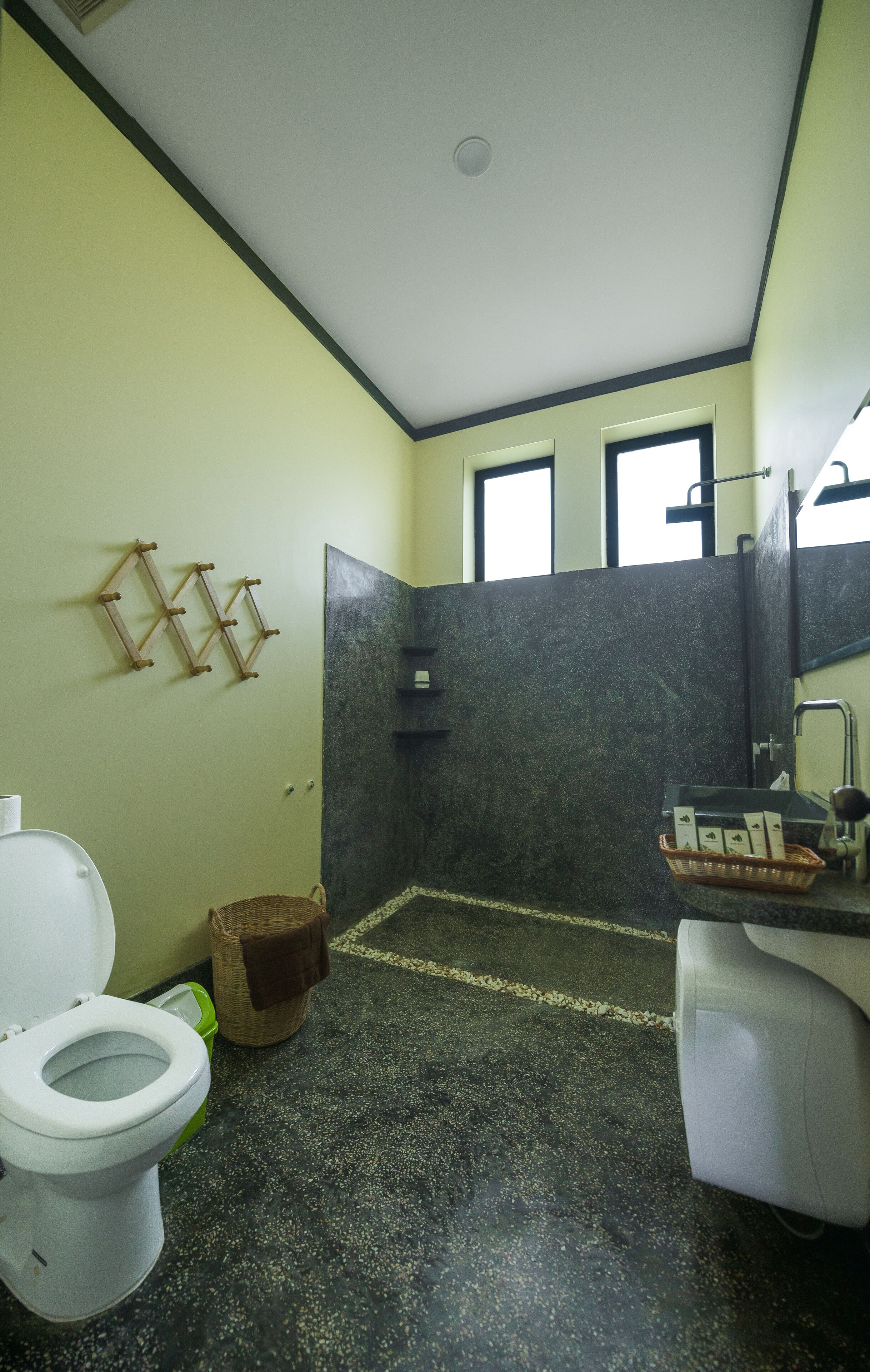 Ein Badezimmer mit Toilette, Waschbecken mit Spiegel und Duschbereich.