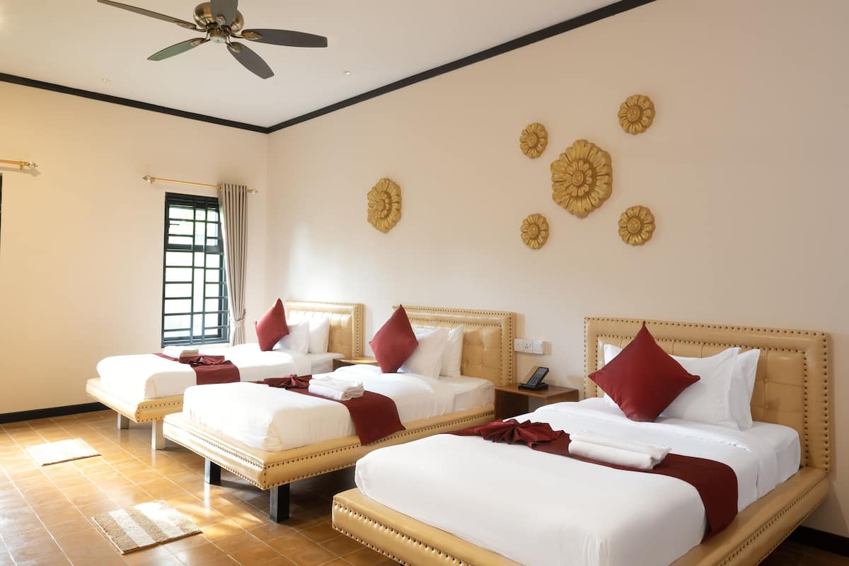 A hotel room with three beds, a ceiling fan, and decorative wall art.