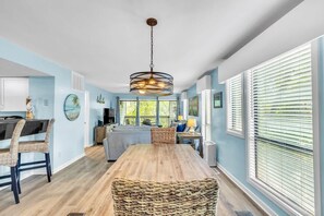 A spacious kitchen with a wooden dining table, wicker chairs, and a hanging light fixture. - Pet Friendly Villa, Pool Beach & Golf! Hilton Head (Hilton Head Island)