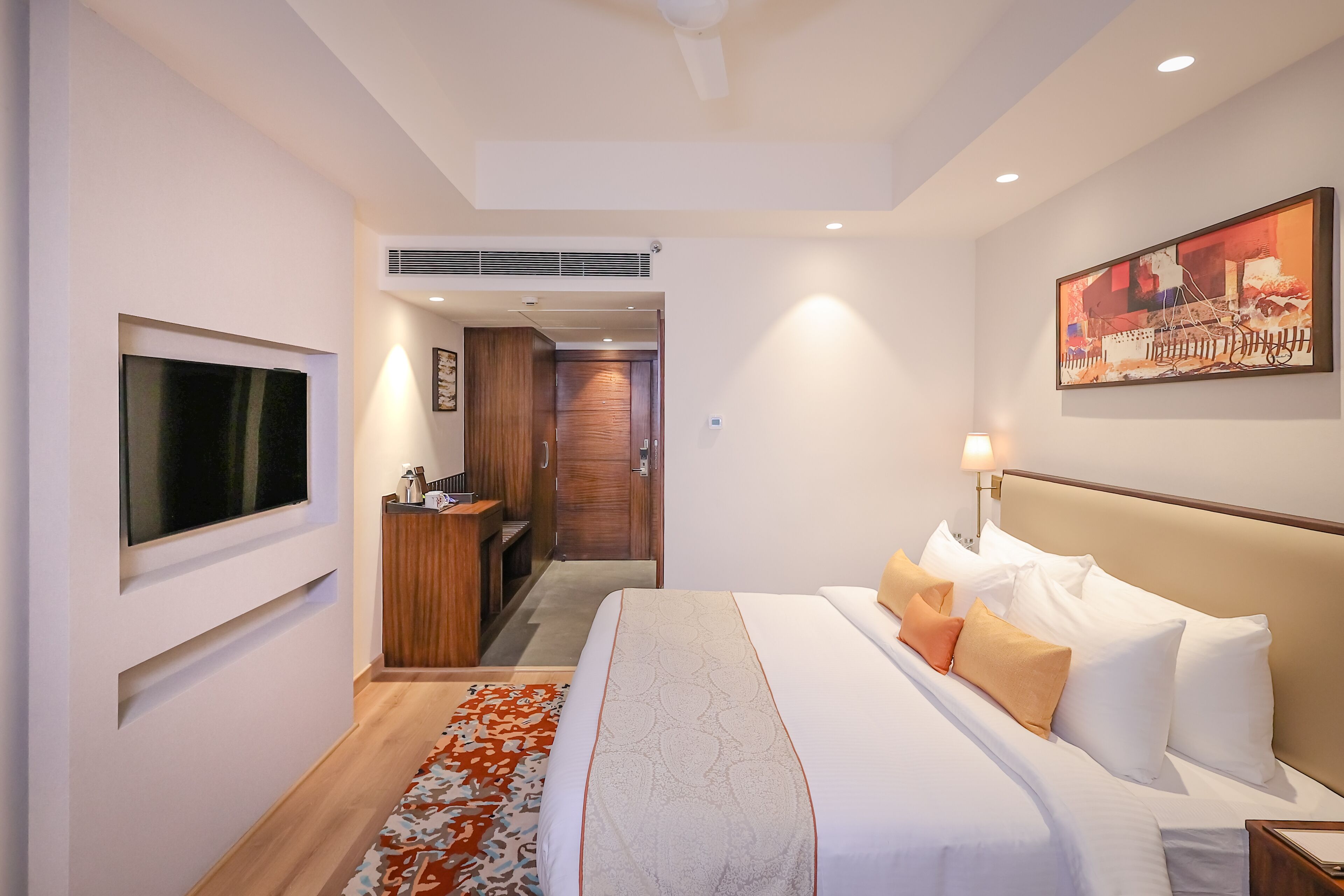 Habitación de hotel con cama, televisión, escritorio y un cuadro en la pared.