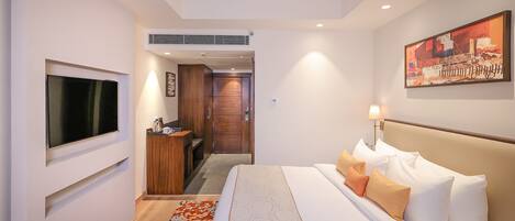 Habitación de hotel con cama, televisión, escritorio y un cuadro en la pared.