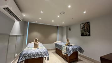 Two beds with patterned bedspreads, a wall-mounted artwork, and a large window.