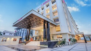 Ein modernes Hotel mit einem markanten Eingang, großen Fenstern und einem überdachten Bereich mit Stufen zum Eingang.