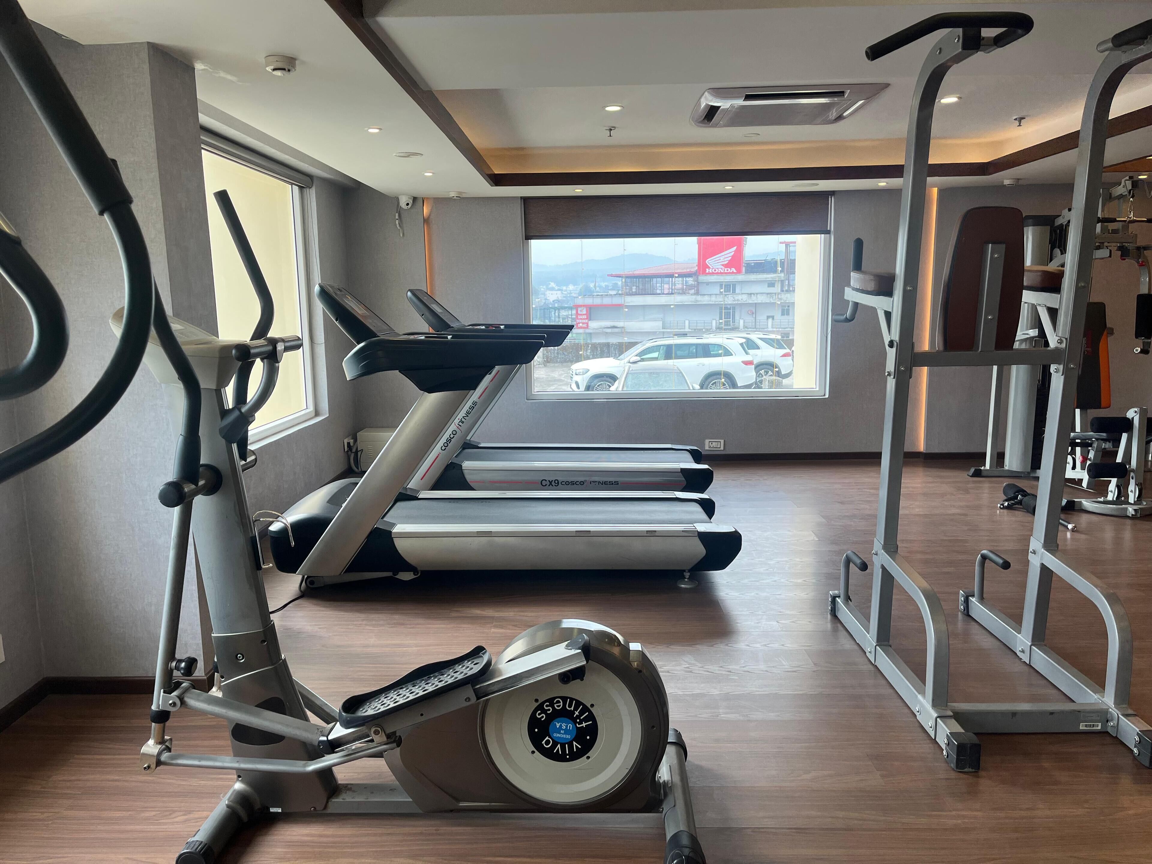 Un gimnasio con cintas de correr, bicicletas estáticas y equipo de levantamiento de pesas.
