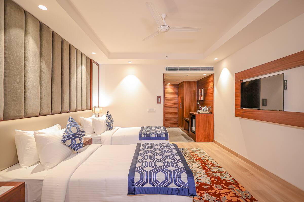A hotel room with two beds, a ceiling fan, a large mirror, and a wooden panel wall.