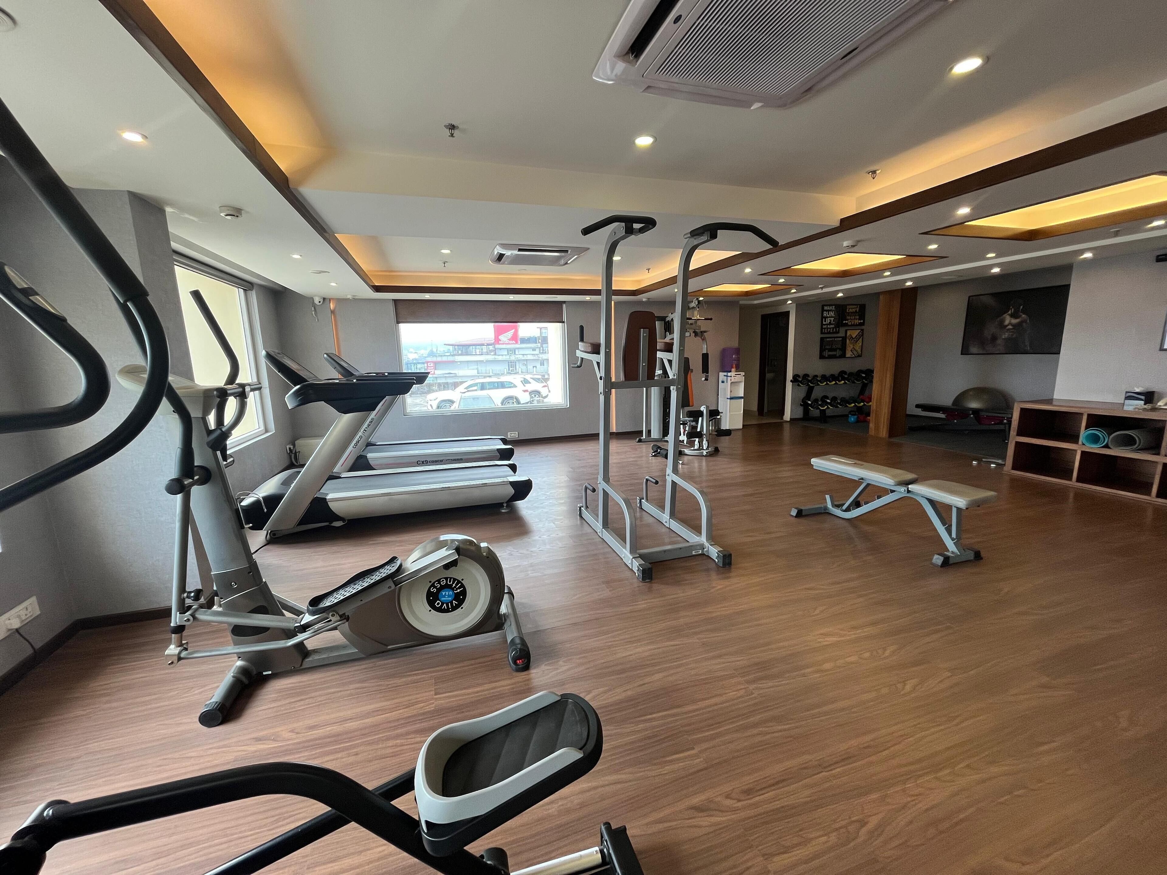 A gym with treadmills, elliptical machines, a bench press, and weightlifting equipment.