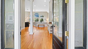 A spacious room with a large bed, a desk, and a view of the outdoors through large windows. - Gorgeous newly renovated home w/ private pool and pool table w/ lagoon views. (Hilton Head Island)