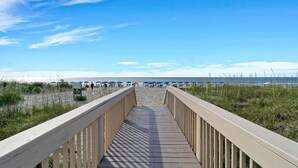 A wooden boardwalk leading to a beach with blue umbrellas. - Gorgeous newly renovated home w/ private pool and pool table w/ lagoon views. (Hilton Head Island)