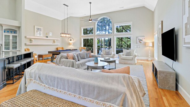 A spacious living room with a pool table, comfortable seating, and large windows. - Gorgeous newly renovated home w/ private pool and pool table w/ lagoon views. (Hilton Head Island)