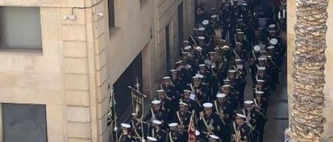 A group of uniformed personnel marching in a narrow street flanked by buildings.