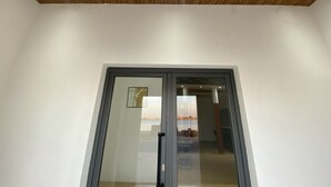 A modern interior with a wooden ceiling, a glass door, and a view of a cityscape through the glass. - FILYS HÔTEL (St. Louis)