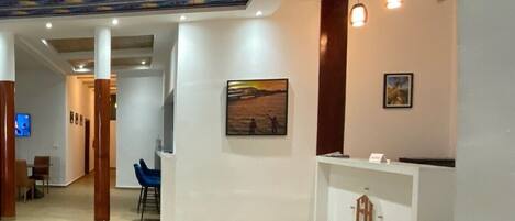 A reception area with a white desk, a framed picture on the wall, and a ceiling with a blue and yellow pattern.