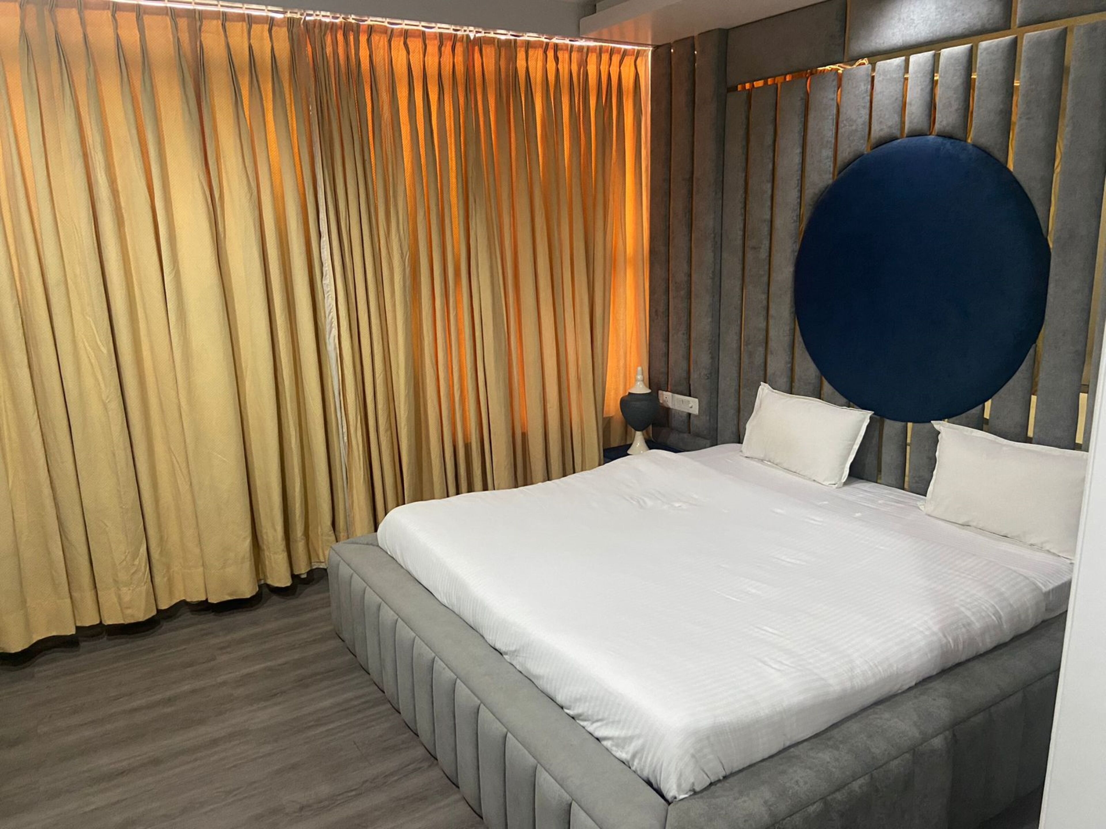 Ein modernes Schlafzimmer mit einem großen Bett, einem runden Kopfteil und einem Vorhang in Goldtönen.