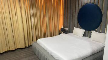 Ein modernes Schlafzimmer mit einem großen Bett, einem runden Kopfteil und einem Vorhang in Goldtönen.