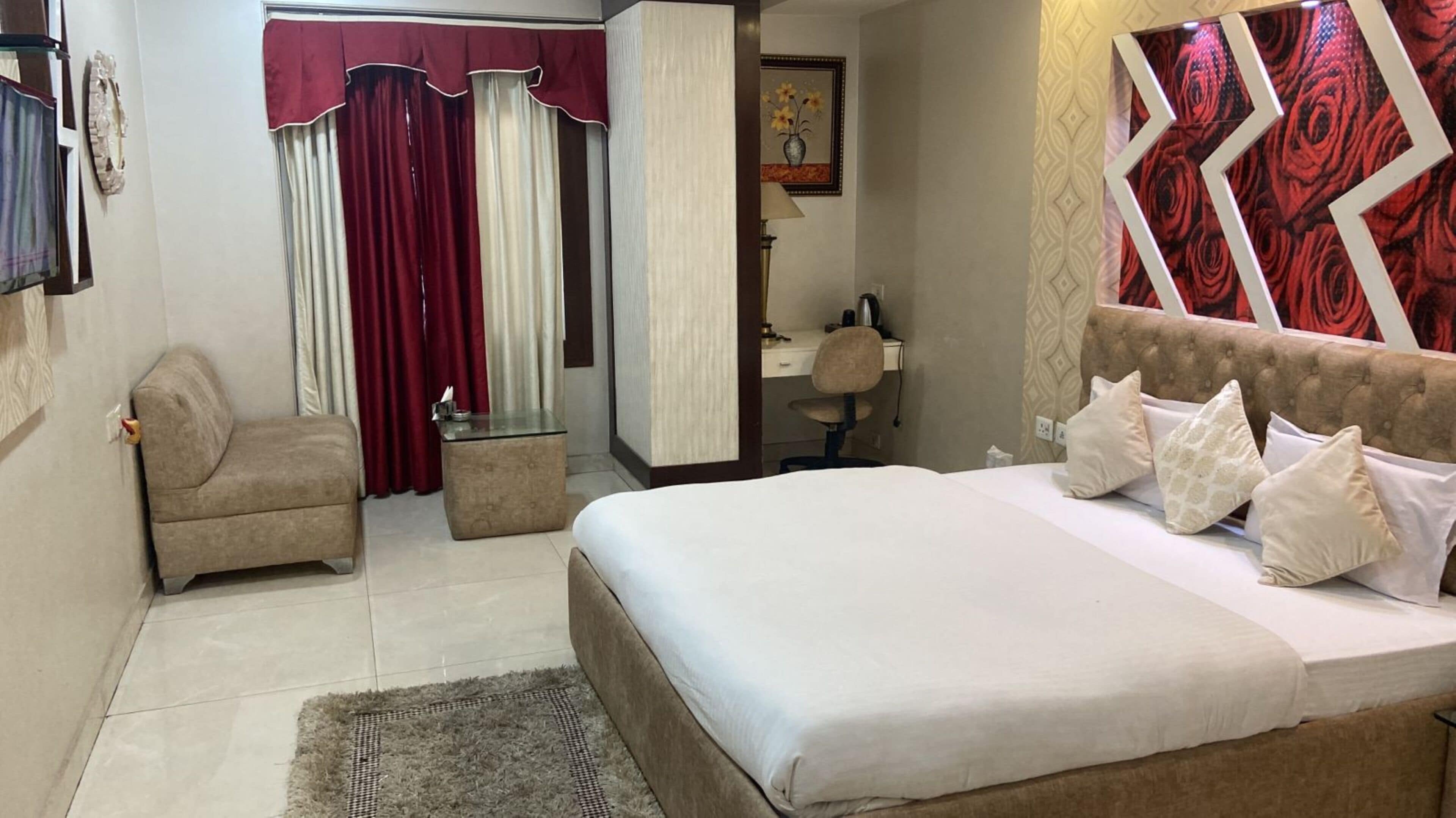 Una camera d'albergo con un letto, una sedia, una scrivania, uno specchio e un bagno visibile attraverso una porta aperta.