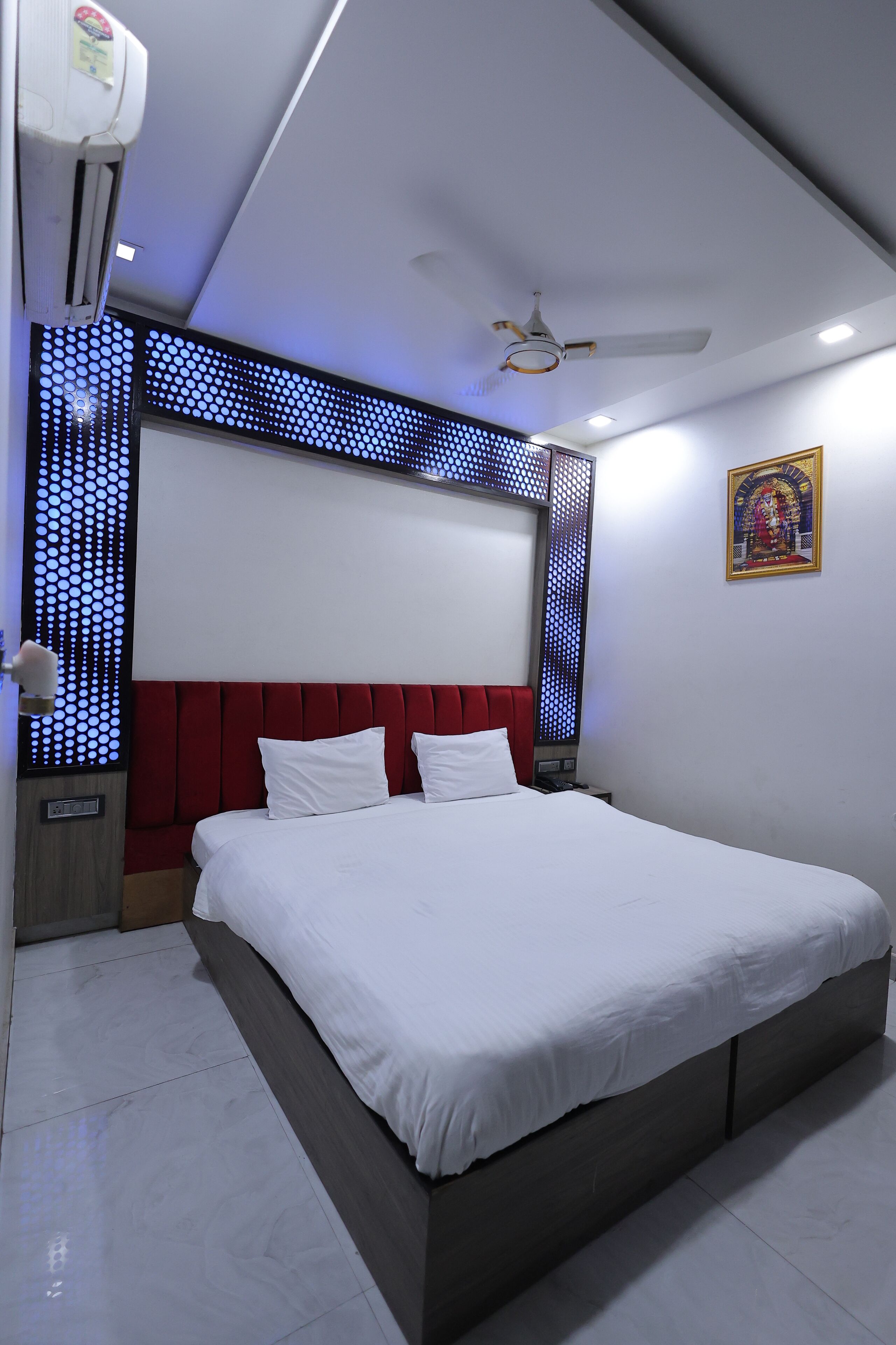 Una habitación de hotel moderna con una cama grande, un ventilador de techo y aire acondicionado instalado en la pared.