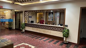 A hotel reception area with a marble floor, a reception desk, and a receptionist. - Hotel Grand Sai - Moradabad, Uttar Pradesh (Moradabad)