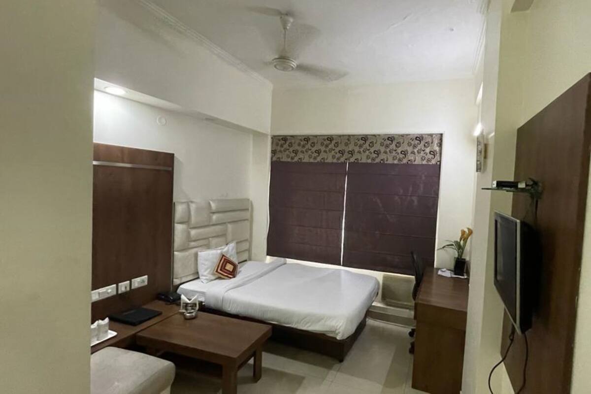 A hotel room with a bed, a desk, a chair, a TV, and a wardrobe.