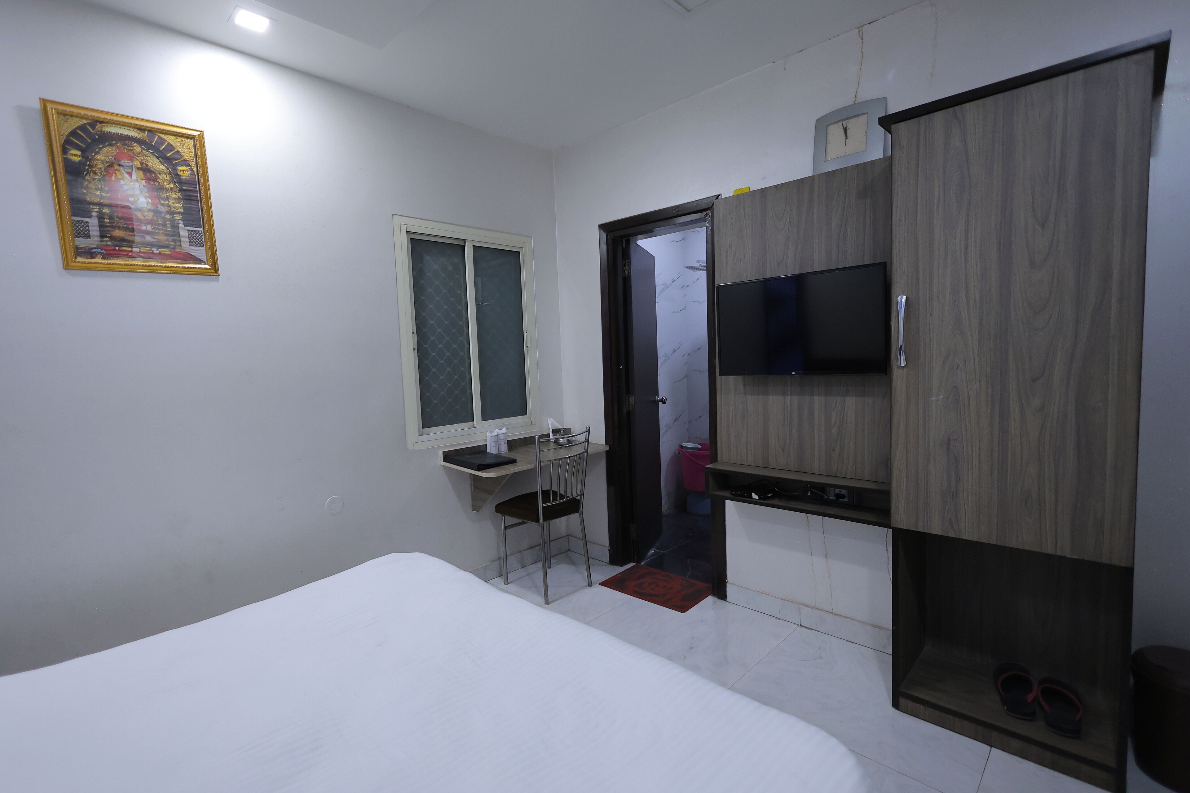 Une chambre à coucher comprenant un lit, un bureau, une chaise, une télévision et une armoire.