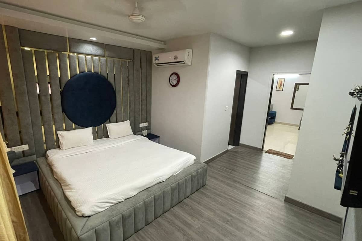 A modern hotel room with a large bed, a round headboard, and a built-in wardrobe.
