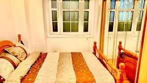 A bedroom with two wooden beds, a window with blinds, and a mirror reflecting part of the room. - Immaculate One Bed in Tower Bridge Luxurious Taste (London)