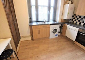 Kitchen equipped with a washing machine, dishwasher, and sink with a faucet, plus wooden cabinets and a countertop.