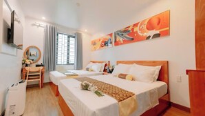 A hotel room with two beds, a desk, a chair, a TV, and artwork on the walls. - Tuan Nam Hotel (Hai Phong)