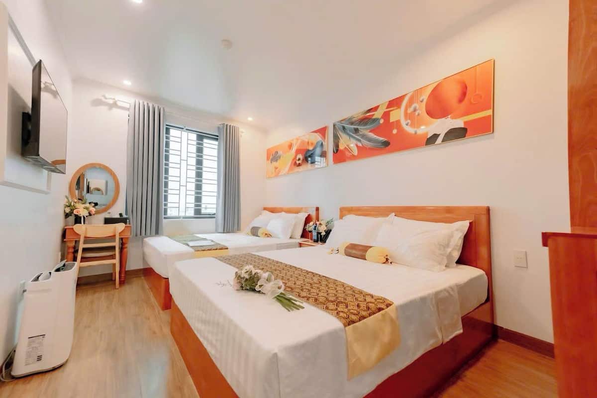 Een hotelkamer met twee bedden, een bureau, een stoel, een televisie en kunstwerken aan de wand.