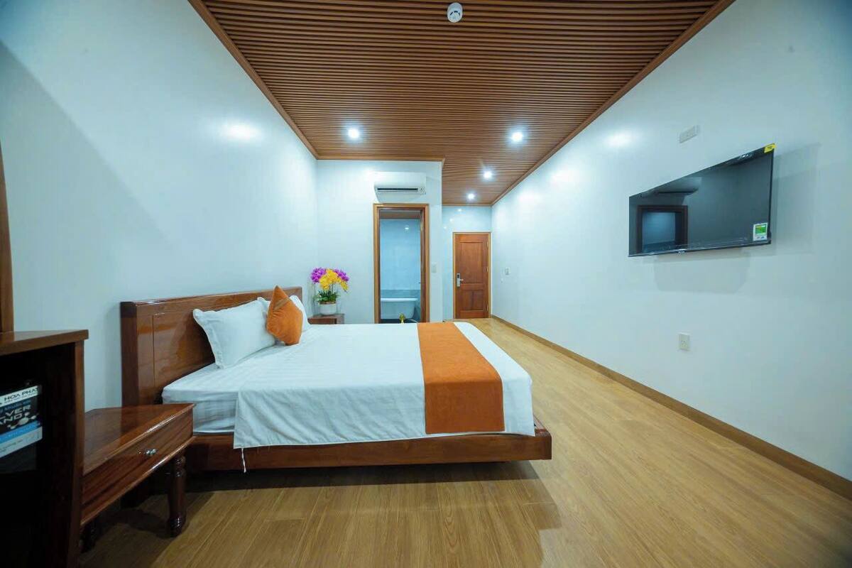 Een slaapkamer met een houten bed, een aan de muur bevestigde televisie en een houten vloer.