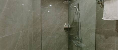 A modern bathroom with a glass-enclosed shower, a toilet, and a towel rack.