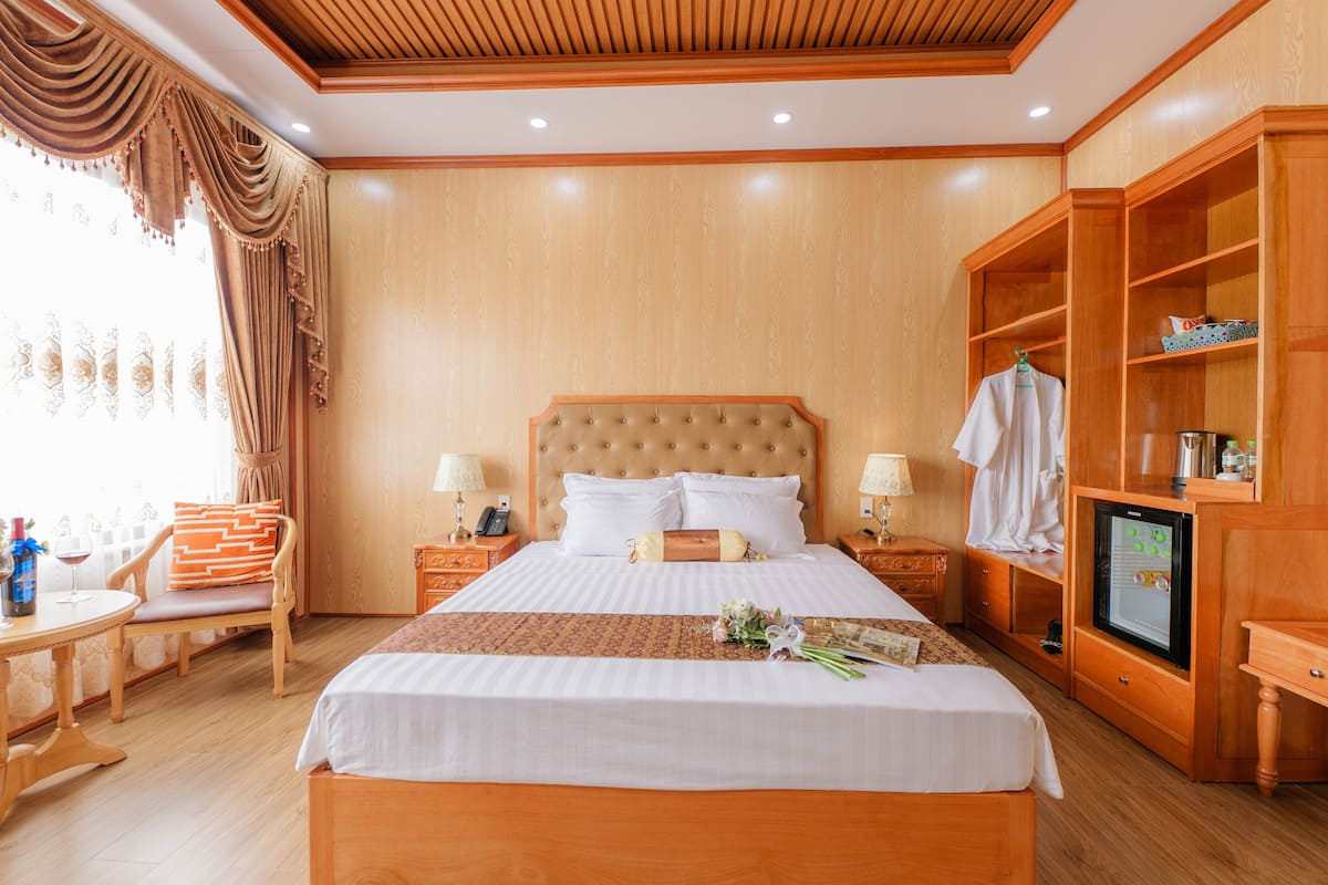 Een hotelkamer met een groot bed, een houten hoofdbord, twee nachtkastjes met lampen, een televisie en een kledingkast.